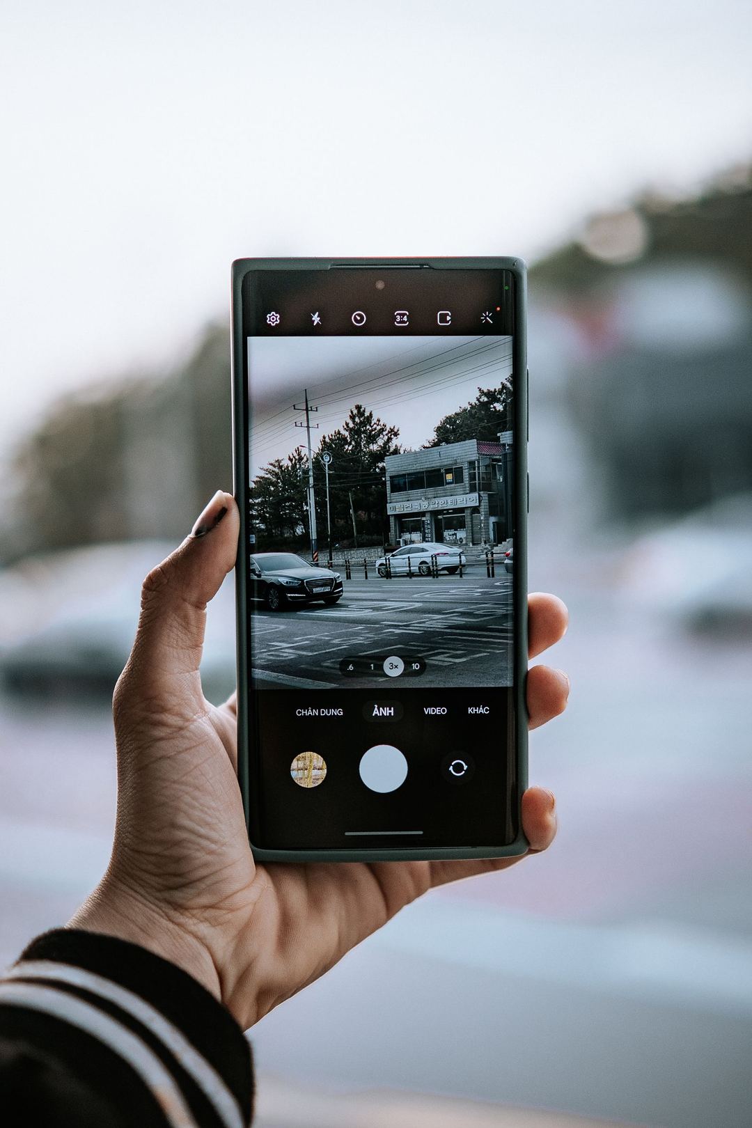 Eine Hand fotografiert ein Auto mit dem Smartphone