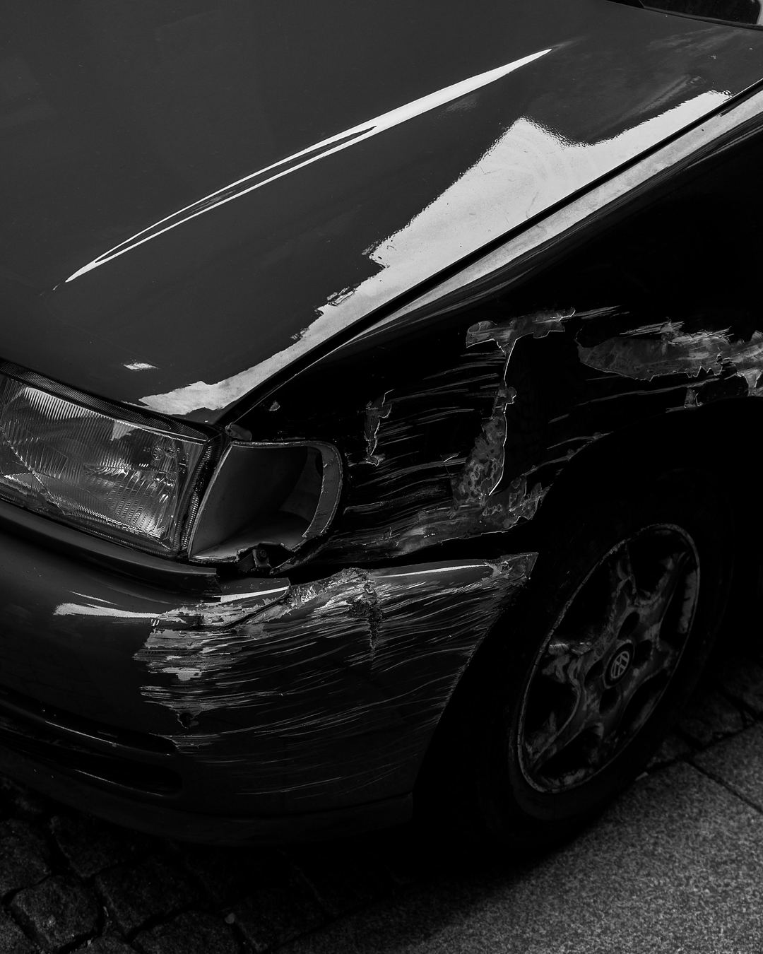 Schwarzes Auto mit Unfallschaden an Stoßfänger, Kotflügel und Blinker