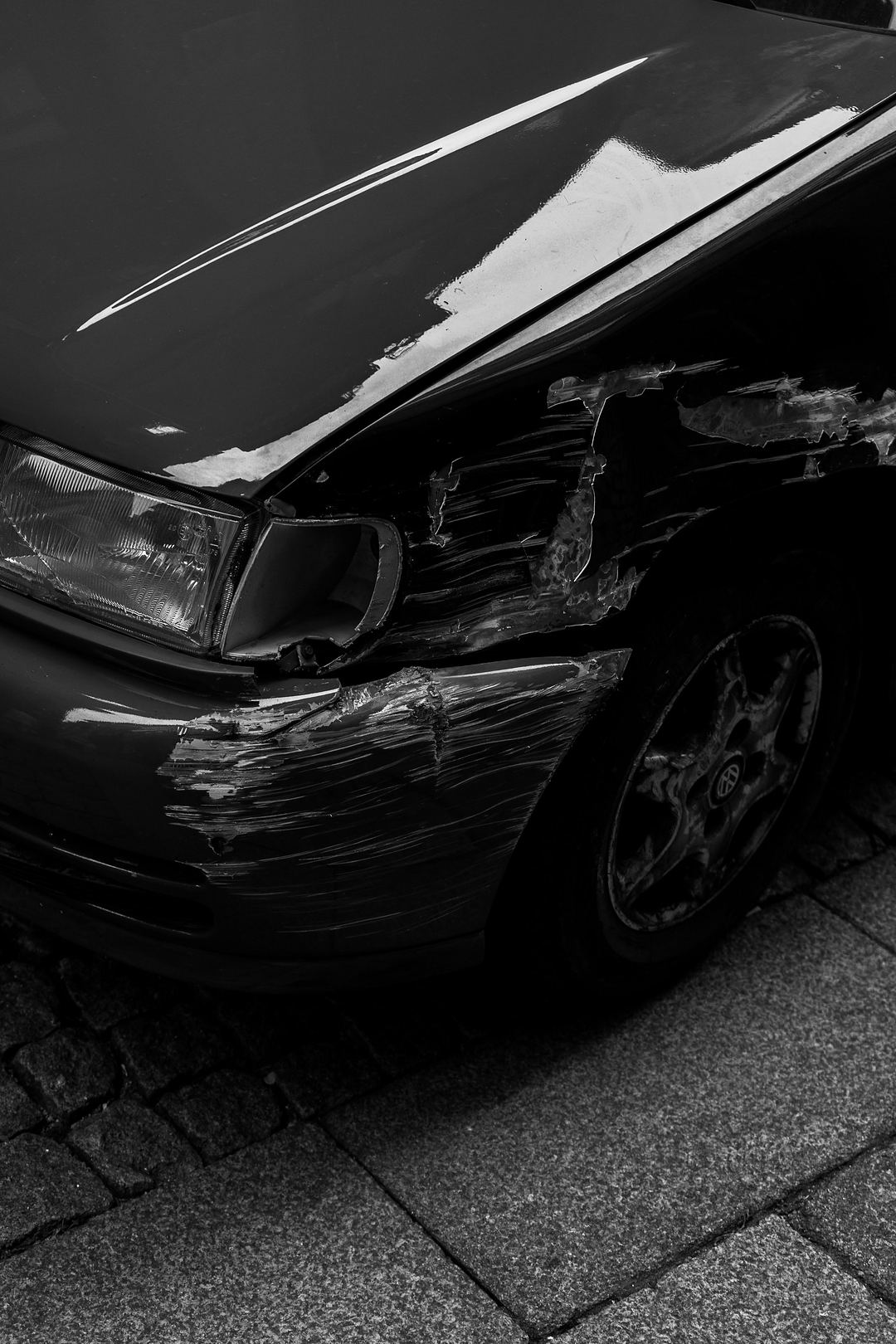 Schwarzes Auto mit Streifschaden am vorderen Kotflügel